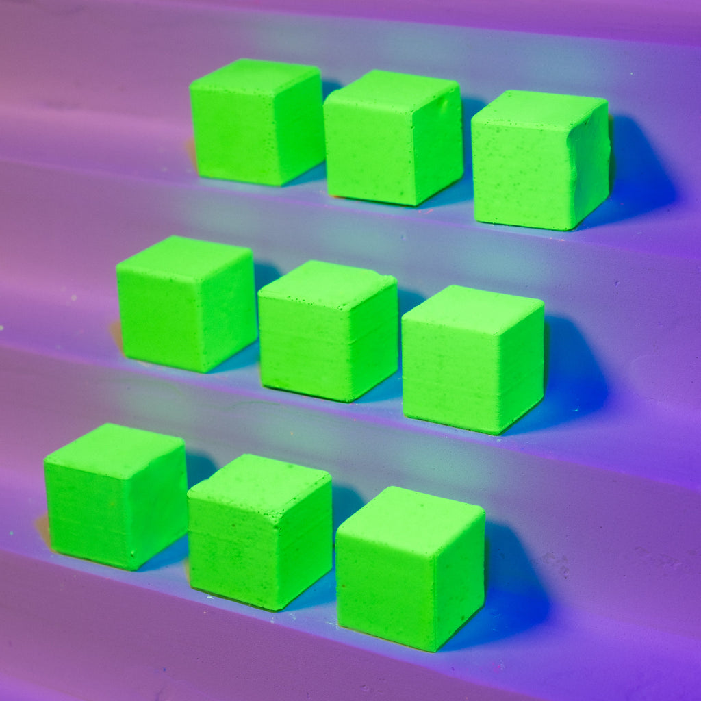 GreenStonelith cubes on a purple surface under UV light