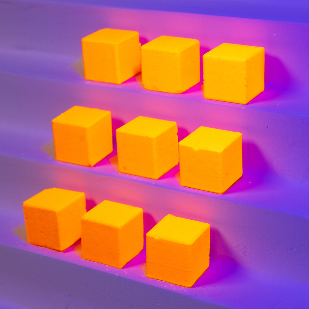 Orange-Yellow cubes on a matte purple surface with a neon pink light.