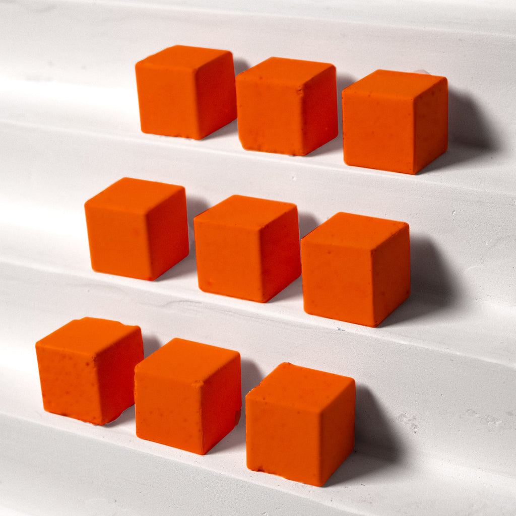 Orange cubes arranged in three rows on a white surface