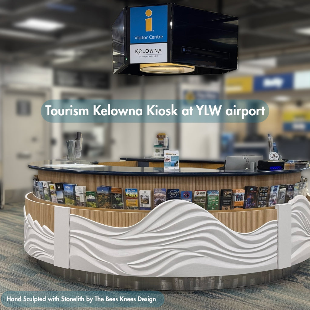 Tourism Kelowna kiosk at YLW airport with promotional materials and a visitor center sign.